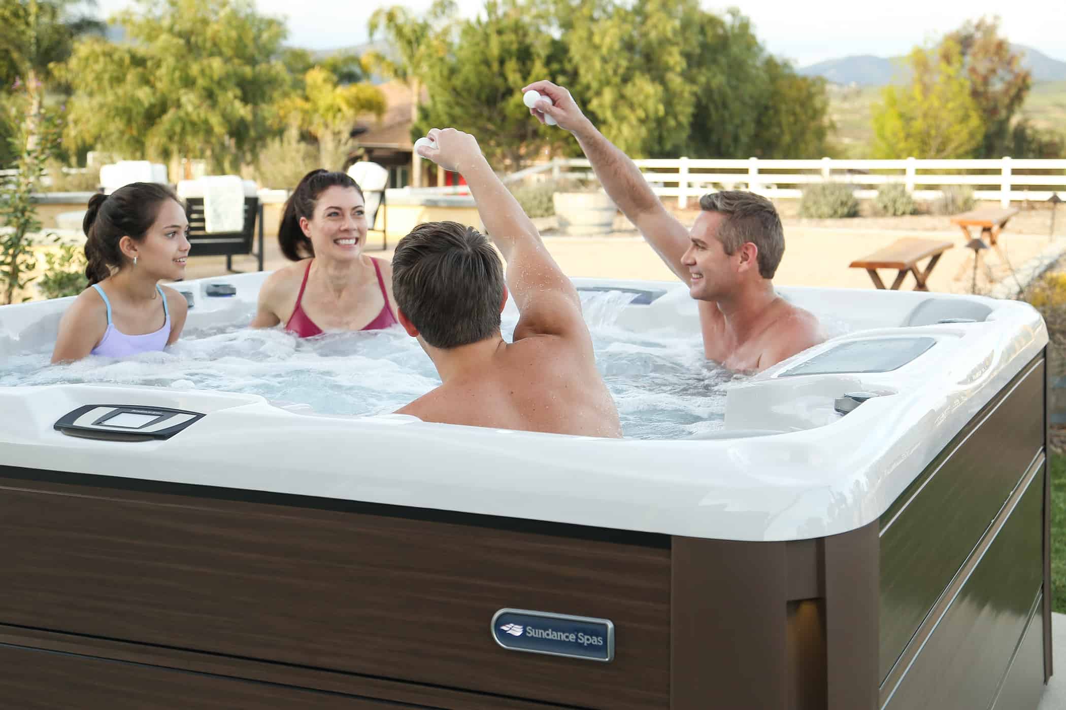 Family of four laughing together in a Sundance hot tub